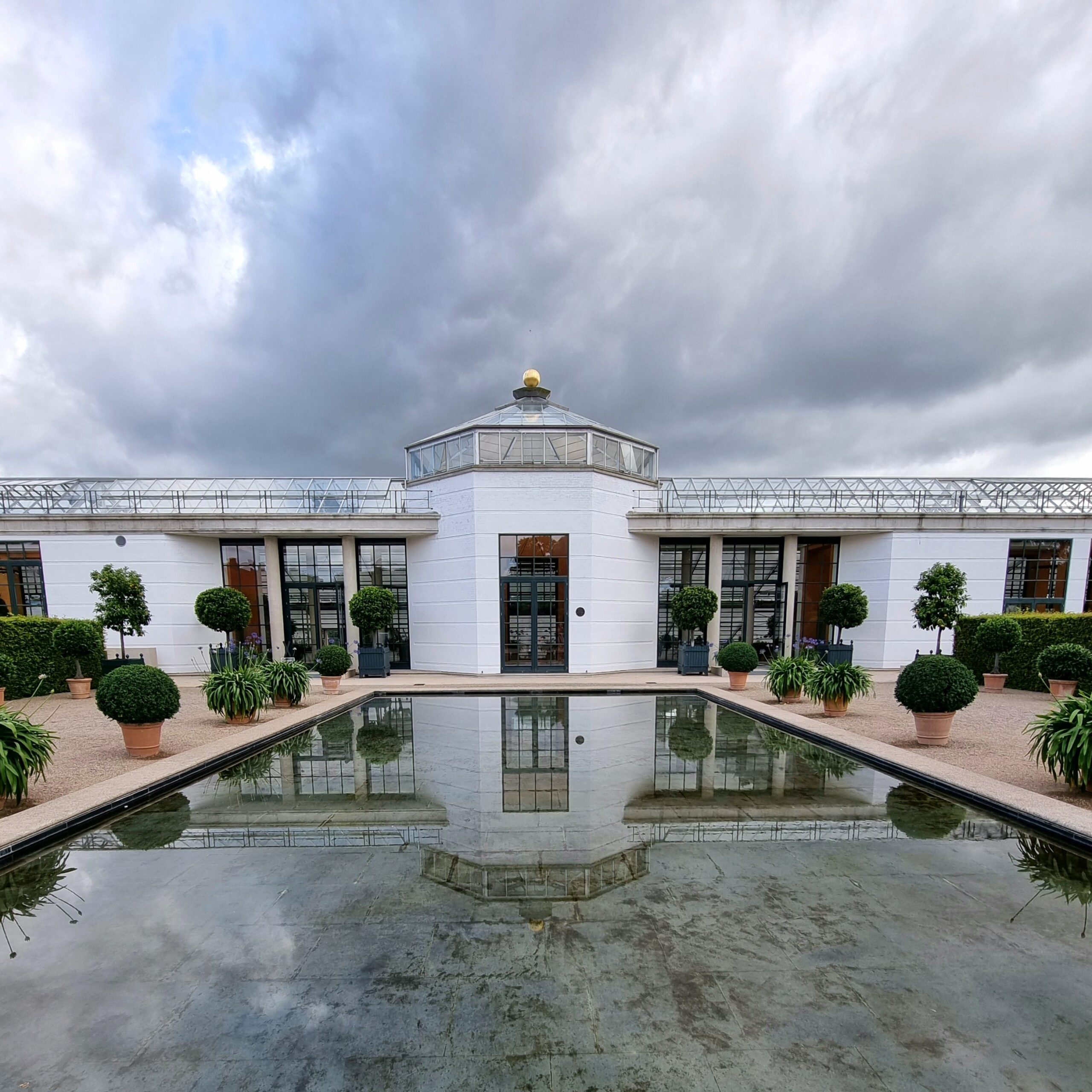 Elegant view of Fredensborg Palace and reflective pool with cloudy sky in Denmark.